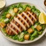 Grilled Chicken Caesar Salad on a plate with romaine, shaved Parmesan, and croutons