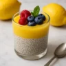 Lemon curd chia pudding topped with berries and mint in a clear glass jar