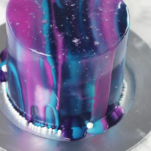 Create Your Own Stunning Galaxy Mirror Glaze Cake at Home! 4 Colorful Galaxy Mirror Glaze Cake with a shiny, reflective surface, resembling outer space.